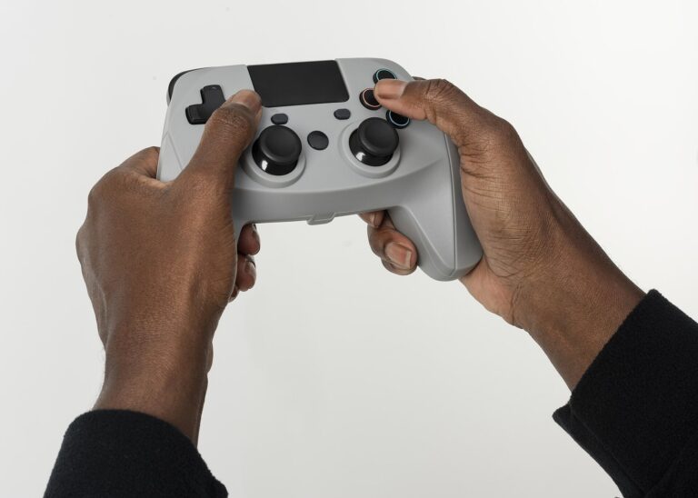 Dos manos sujetan un mando de videojuegos gris sobre un fondo blanco