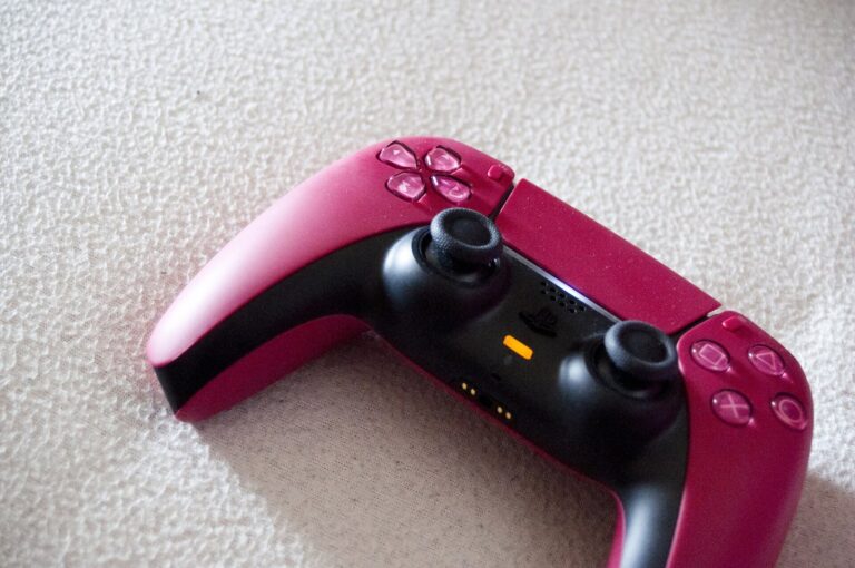 Un mando DualSense de PlayStation 5, rojo y negro, sobre una superficie clara
