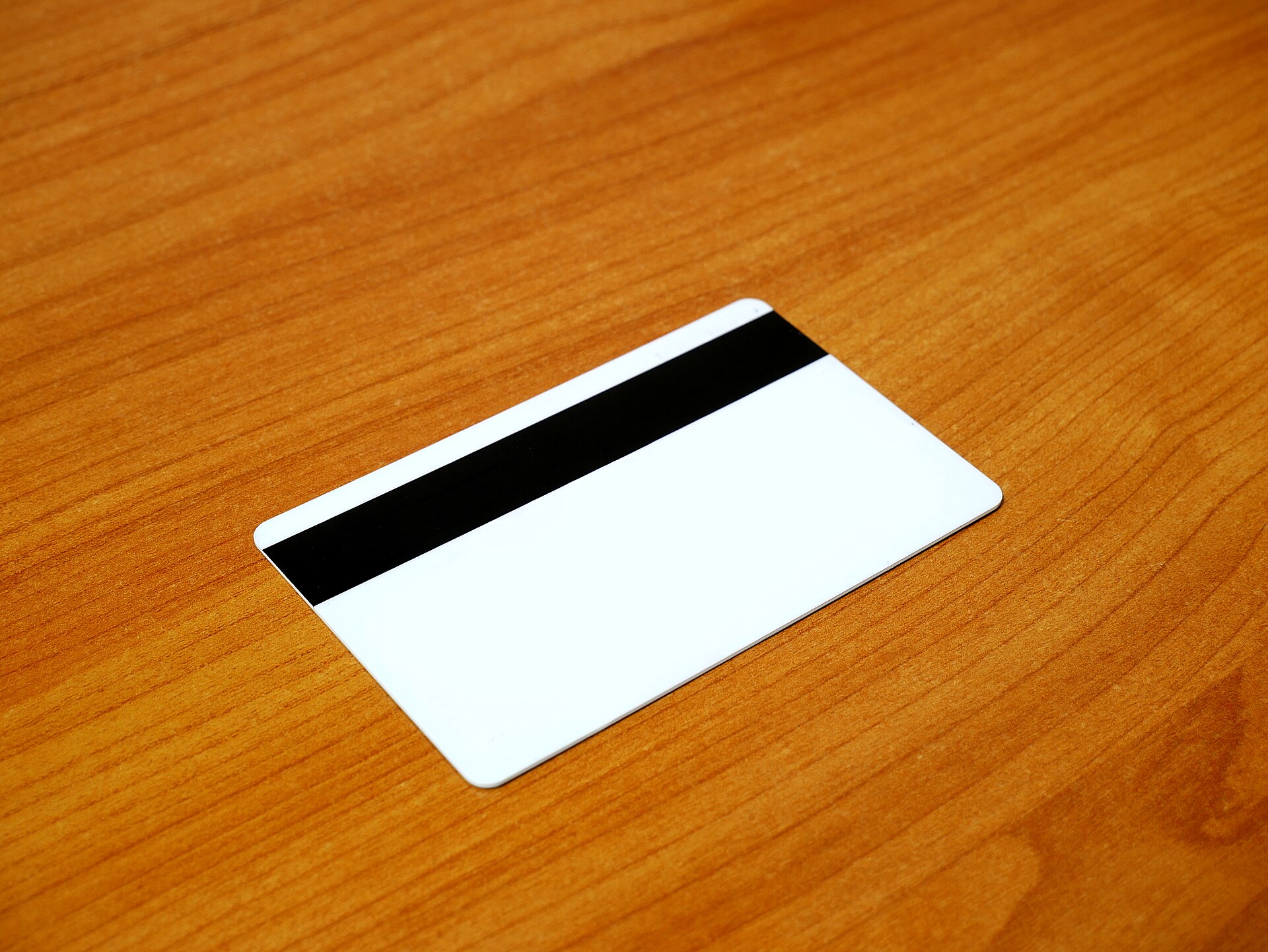 Reverso liso de una tarjeta de pago, con la banda magnética, sobre una mesa de madera