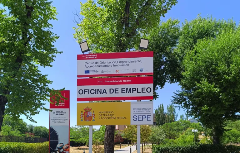 Carteles de la oficina de empleo de Moratalaz, en Madrid, de la Comunidad de Madrid y del Servicio Público de Empleo Estatal, entre árboles