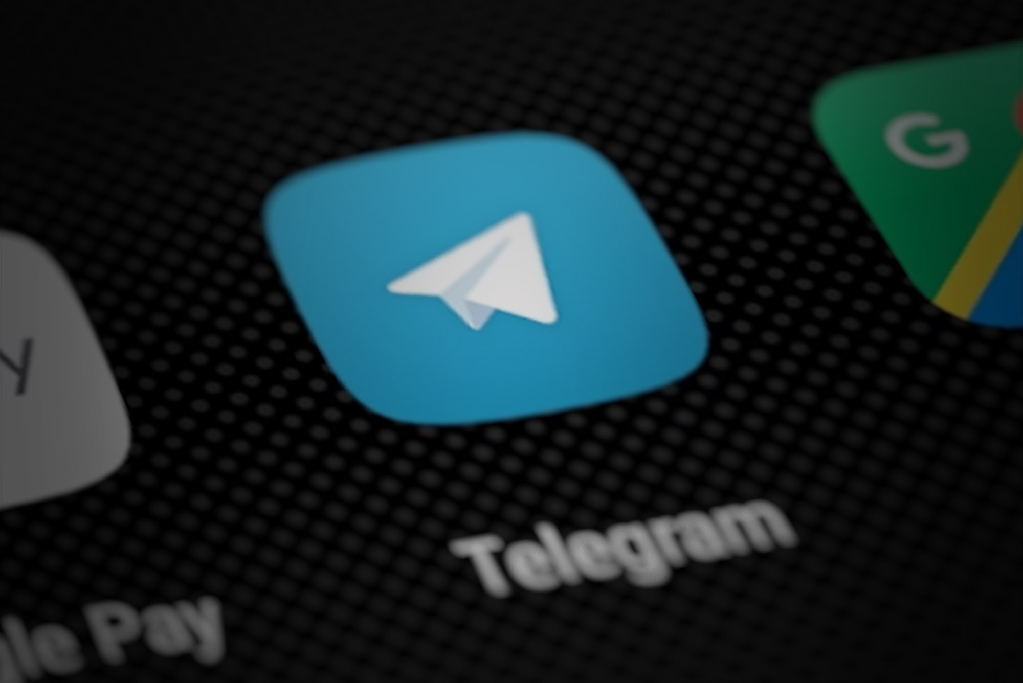 Primer plano del icono azul de la aplicación Telegram en la pantalla de un teléfono móvil, junto a otros iconos desenfocados