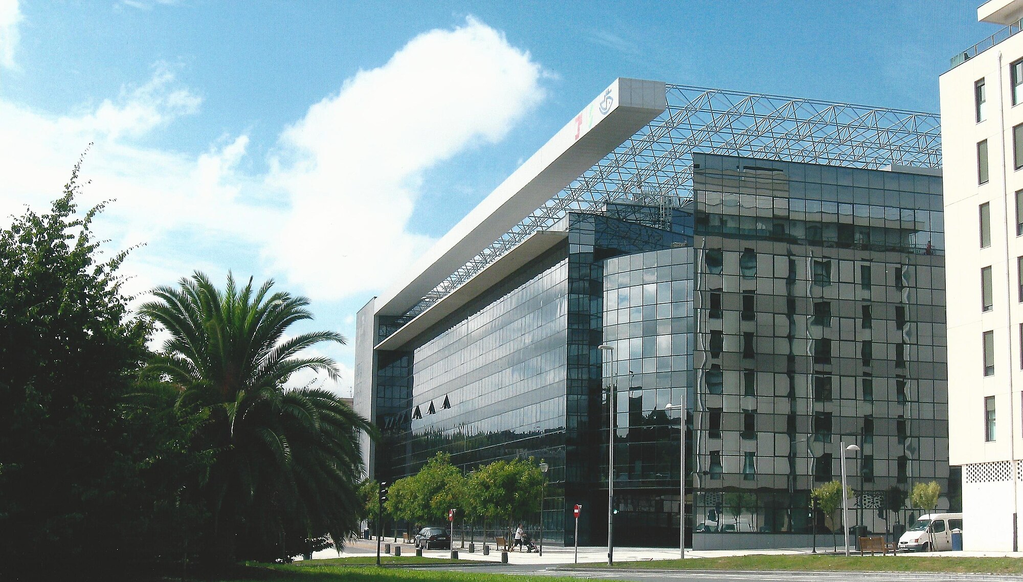 Edificio de cristal del Instituto Nacional de la Seguridad Social en Riberas de Loyola, San Sebastián, con palmeras y árboles delante